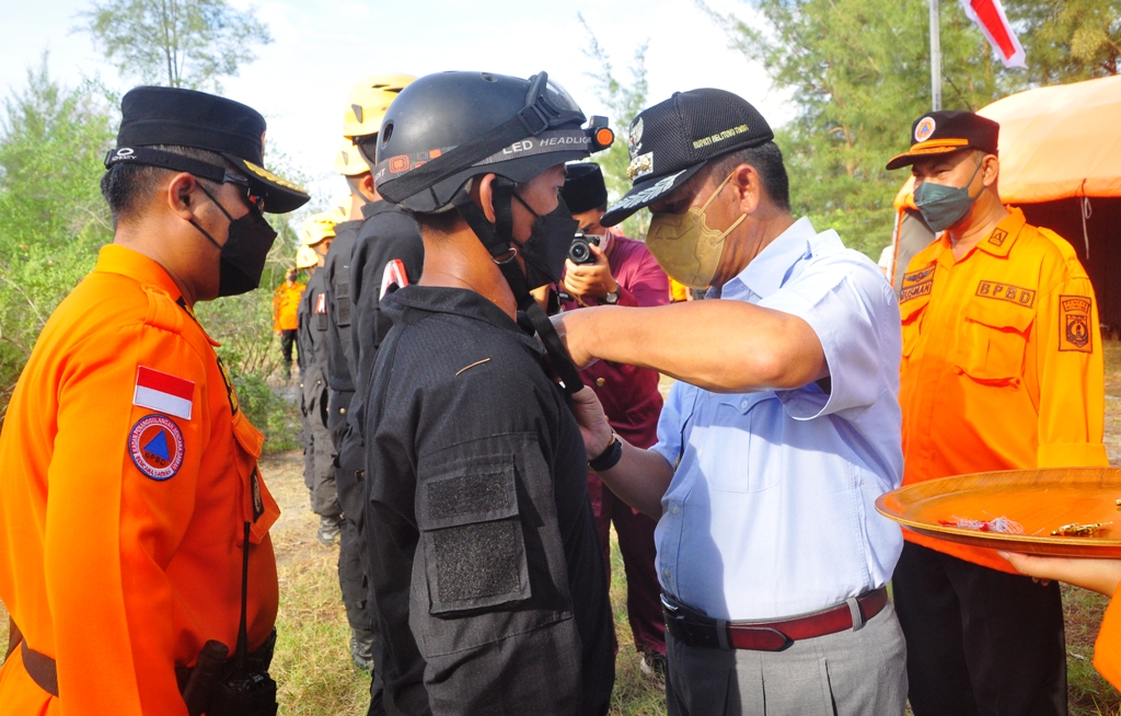 Bupati Beltim saat memasang pin didampingi Kasi dan Kepala pelaksana BPBD